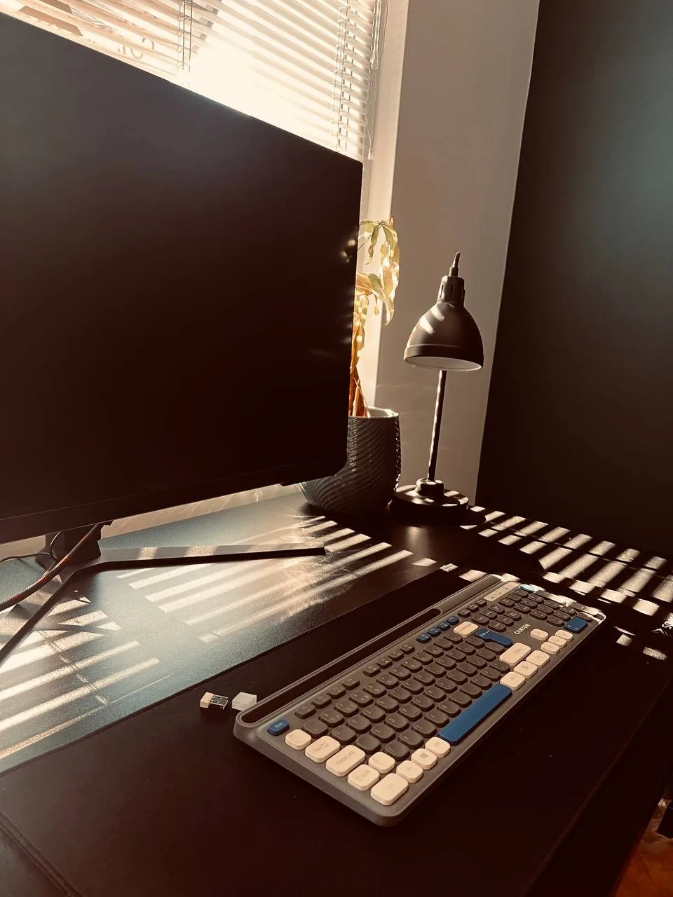 Sunlight across a monitor, keyboard, and desk lamp at Codeburg coworking in Burgas